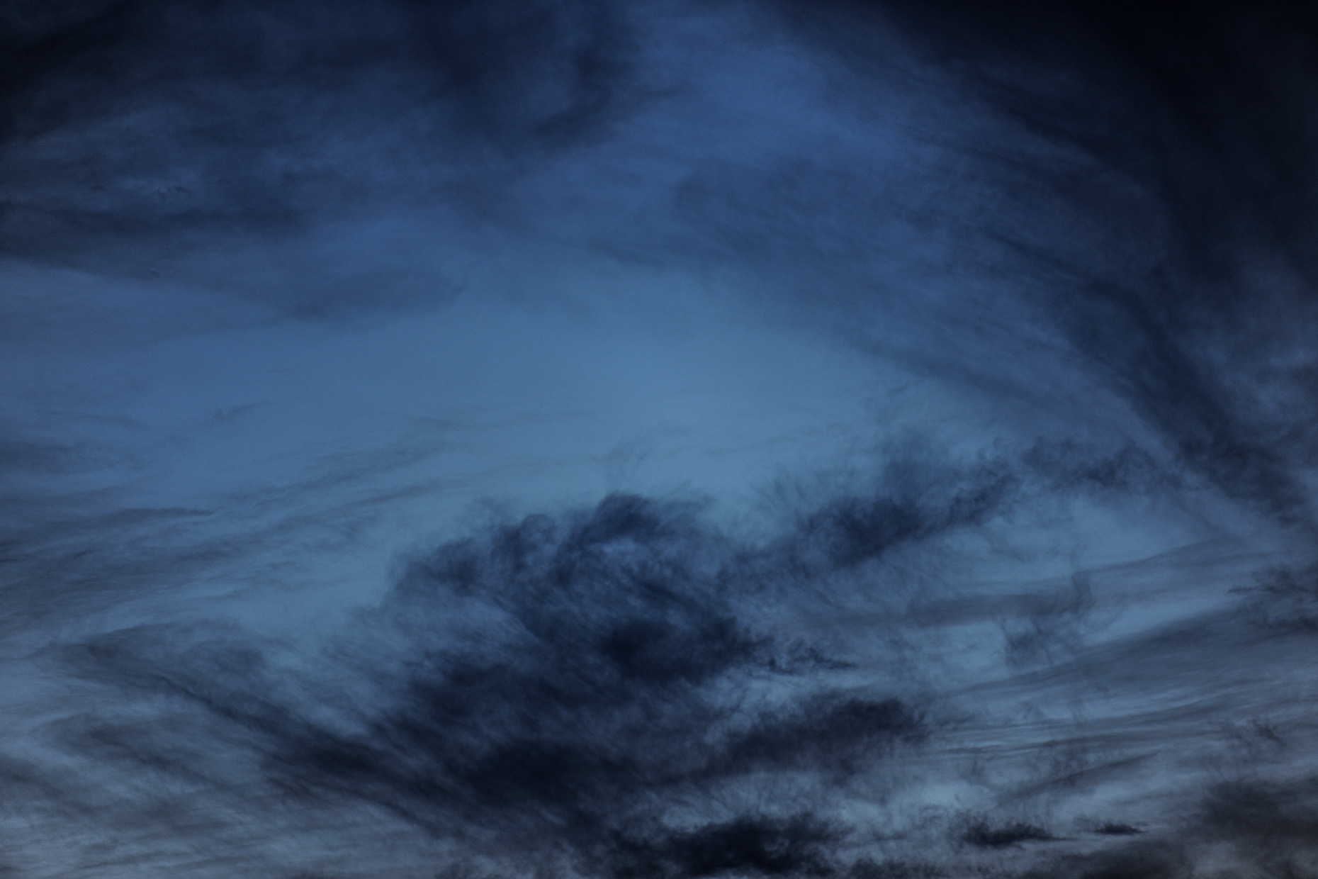 Swirling, white, grey clouds at twilight.