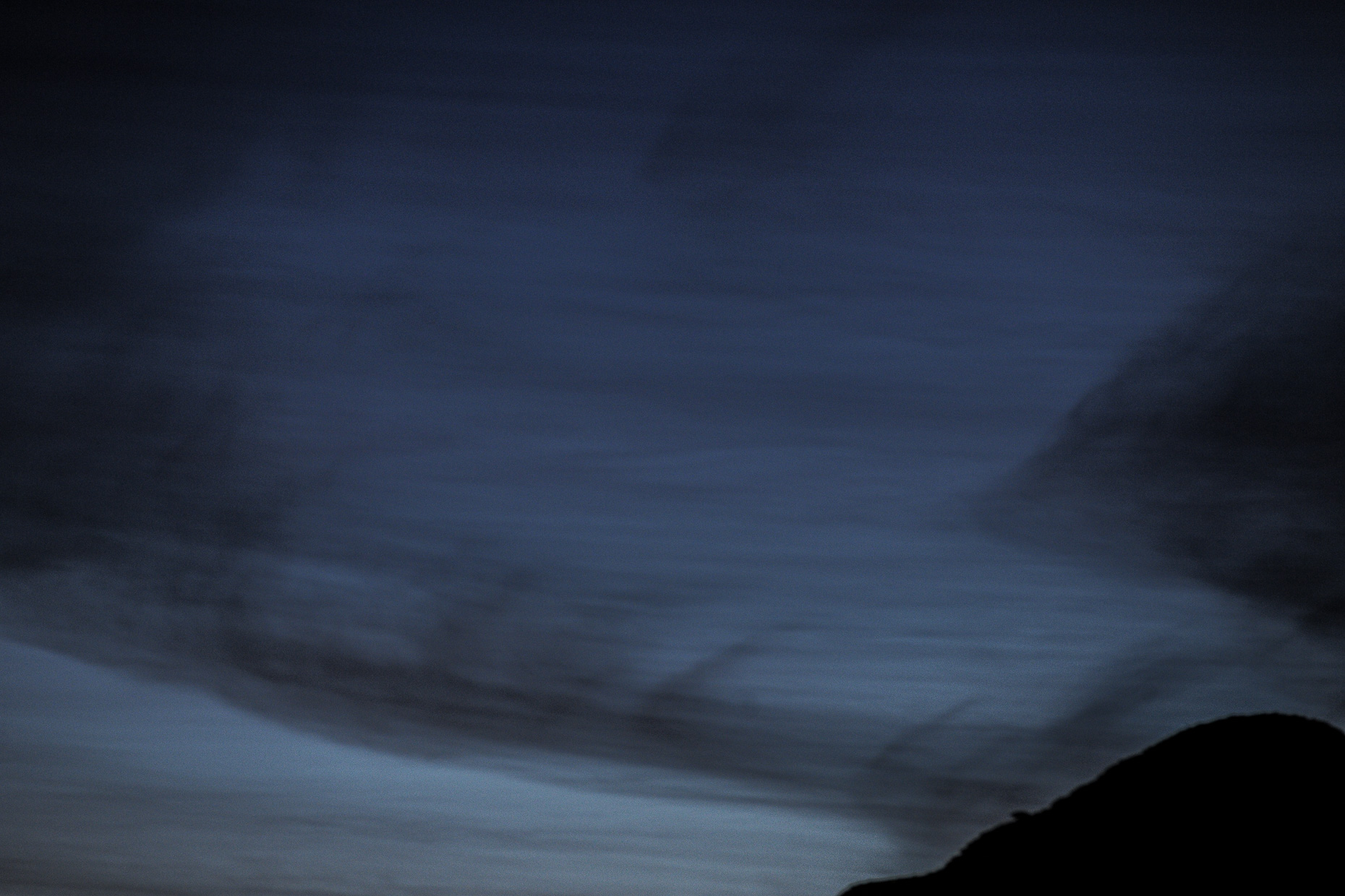 Streaky skies with hill silhouette, photographed at twilight. 