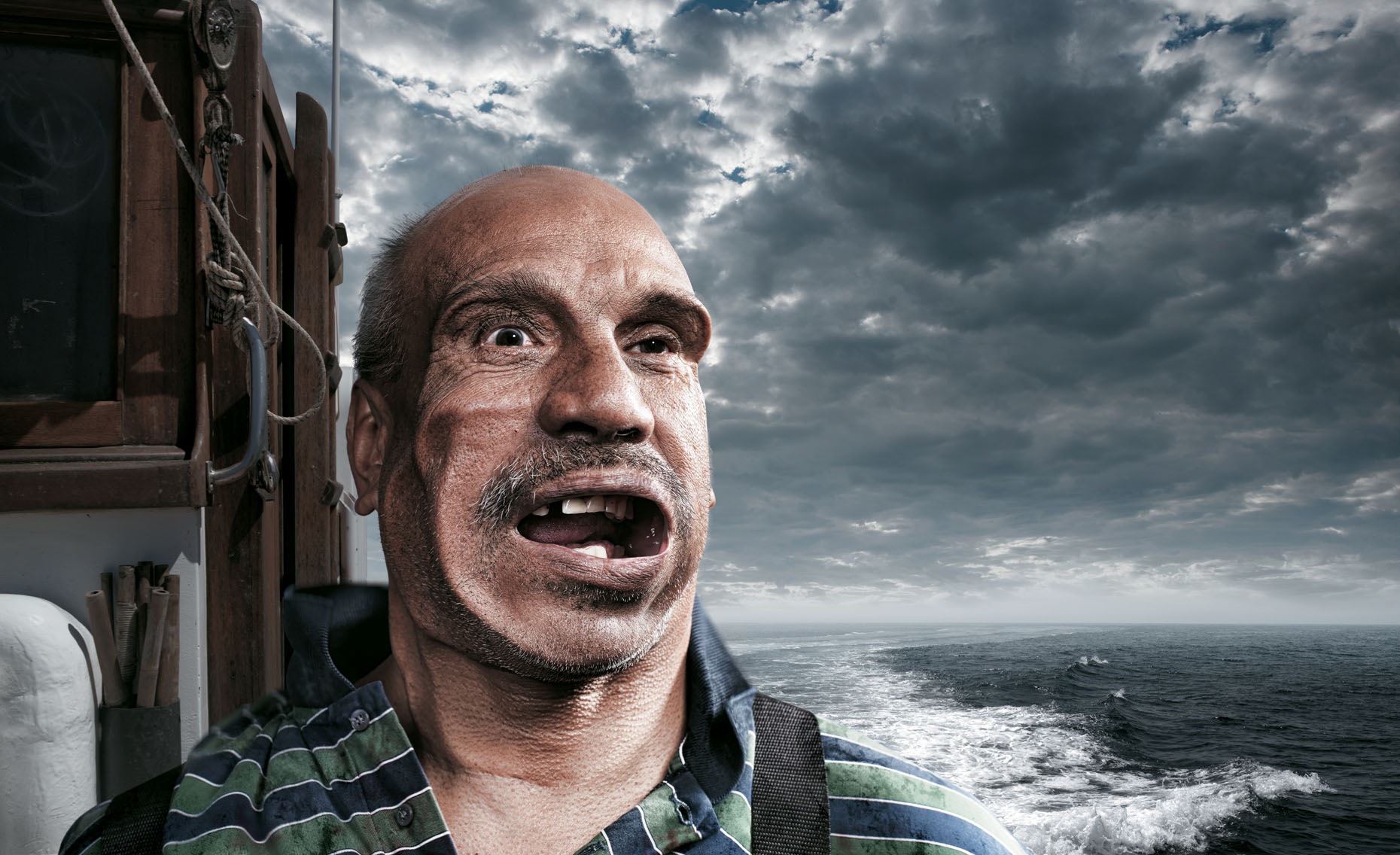 Portrait of a hardy fisherman being battered by a headwind on his boat, in  a stormy sea.