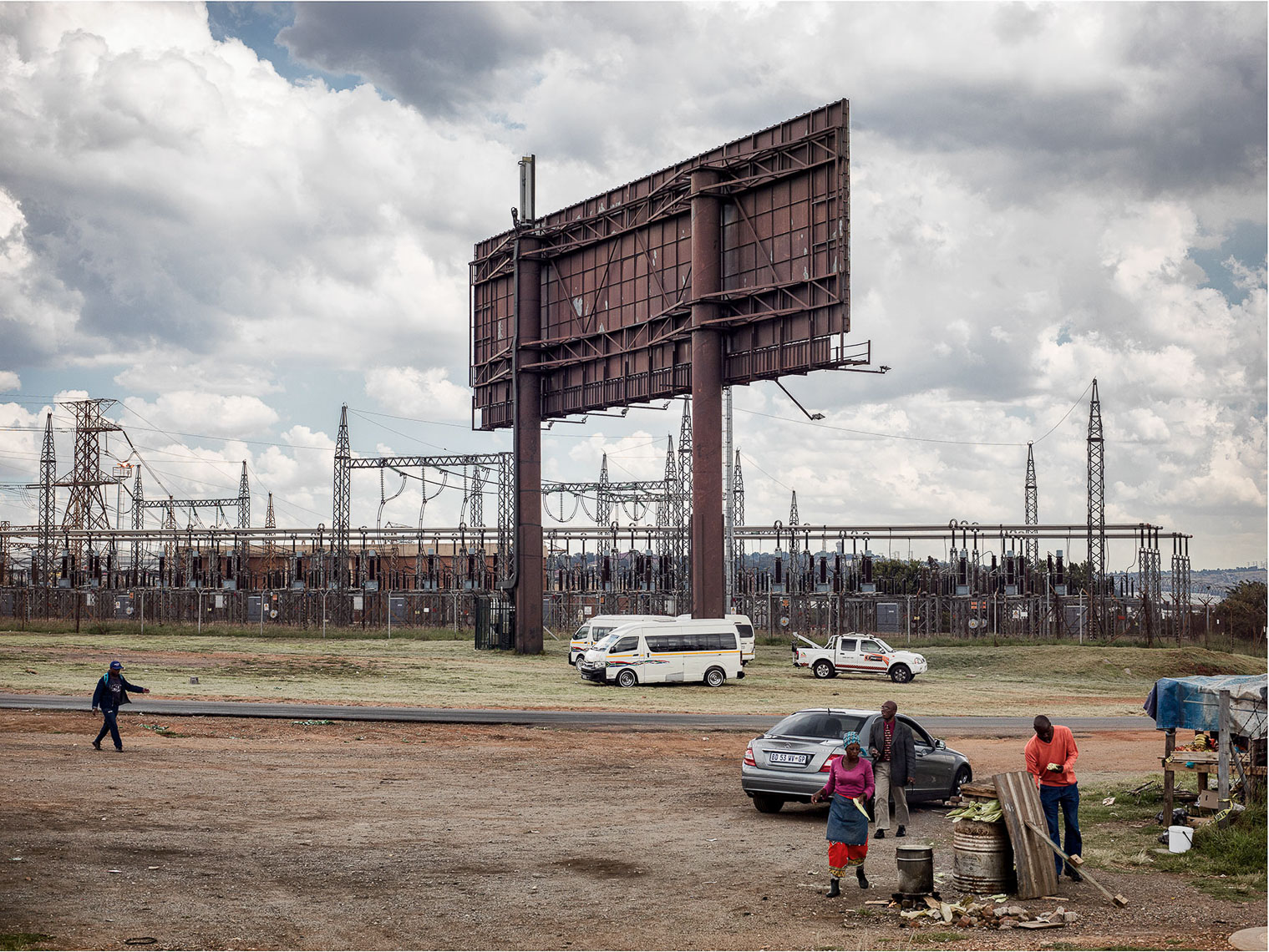 Empty billboard in an industrial landscape with hawkers and taxis. 