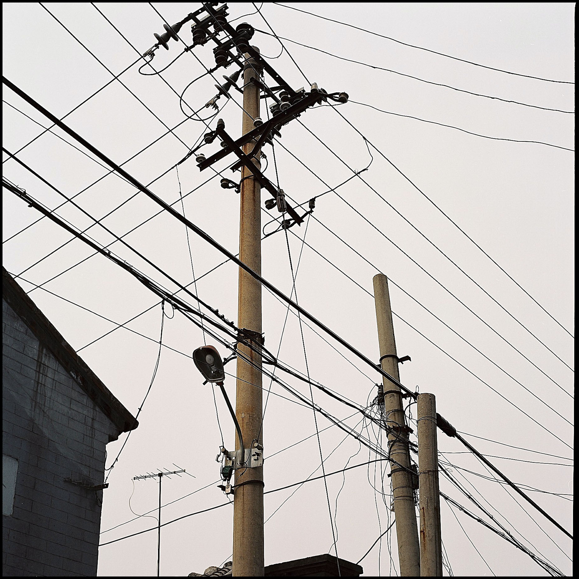 The criss cross of electricity poles and cables above Hutongs of Beijing. 