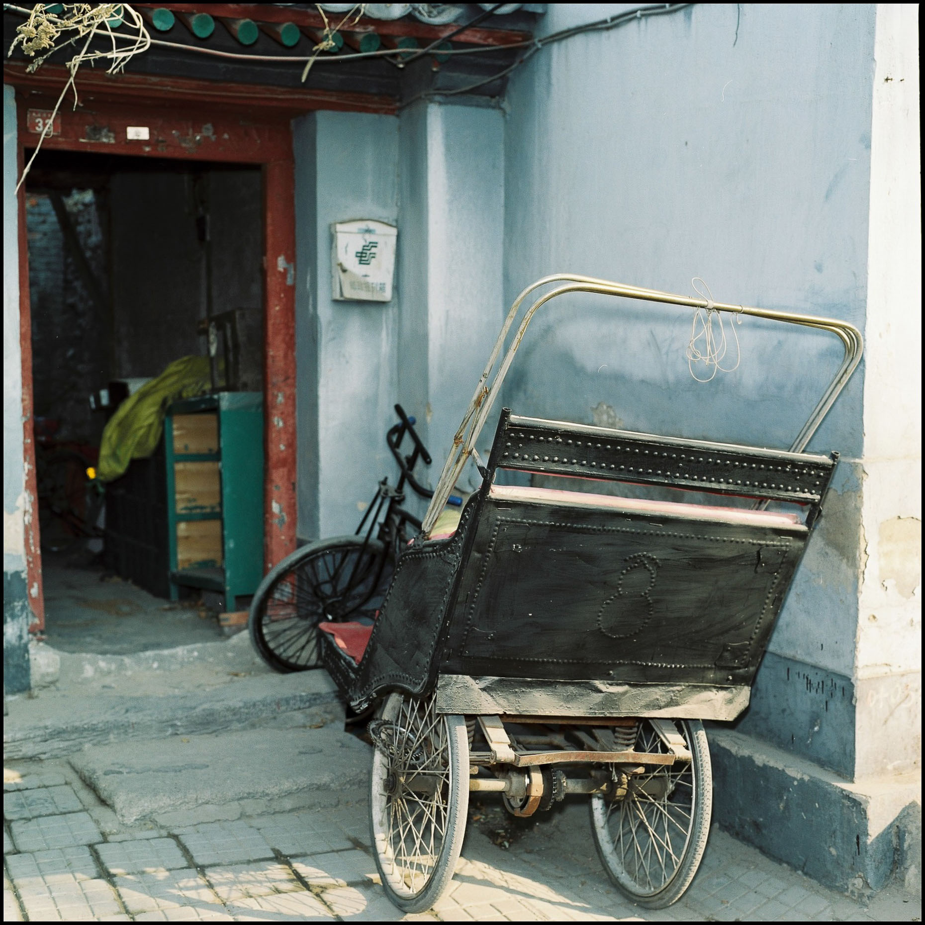 A rickshaw parked outside a chinese residence.