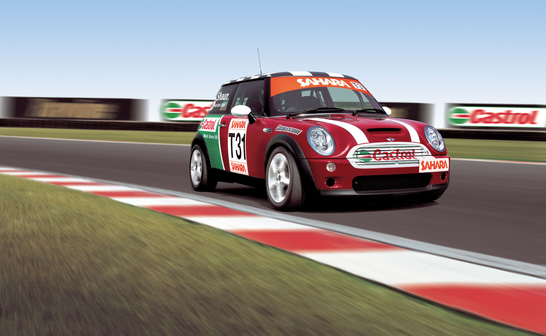 A red Mini Castrol racing around a track. 