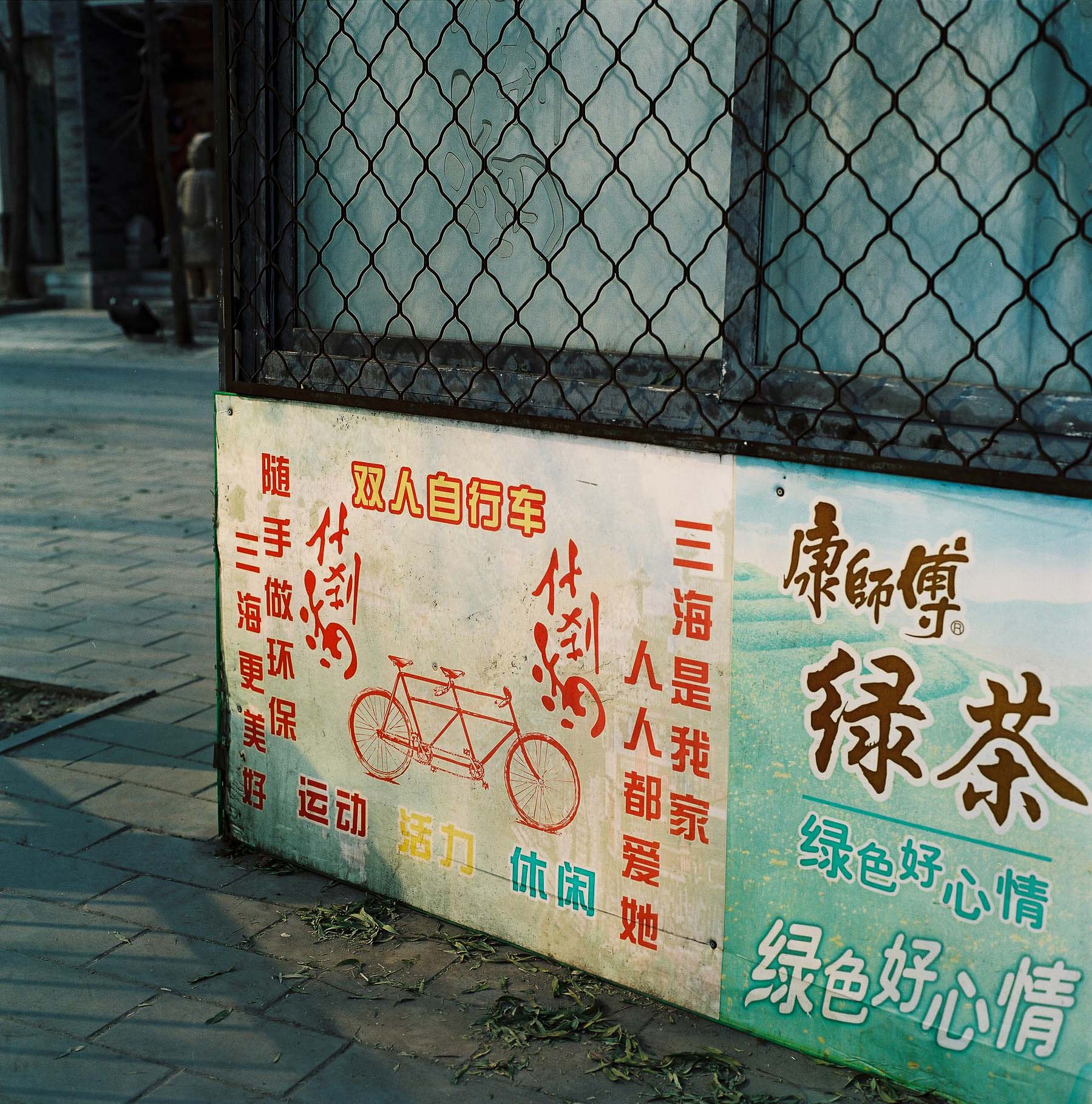 A bicycle sign written in red on a street corner in China.