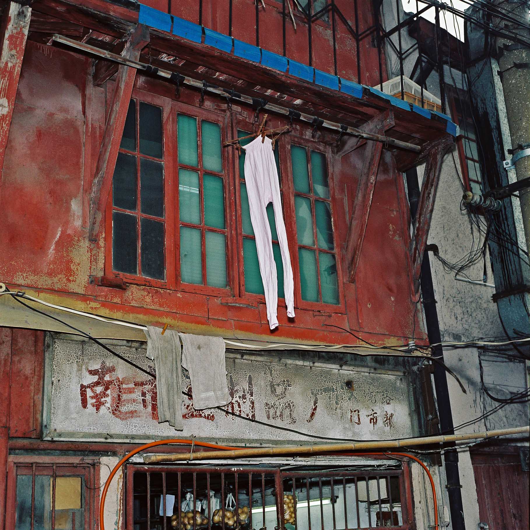 A pair of old long johns drying in front of a red shop window. 