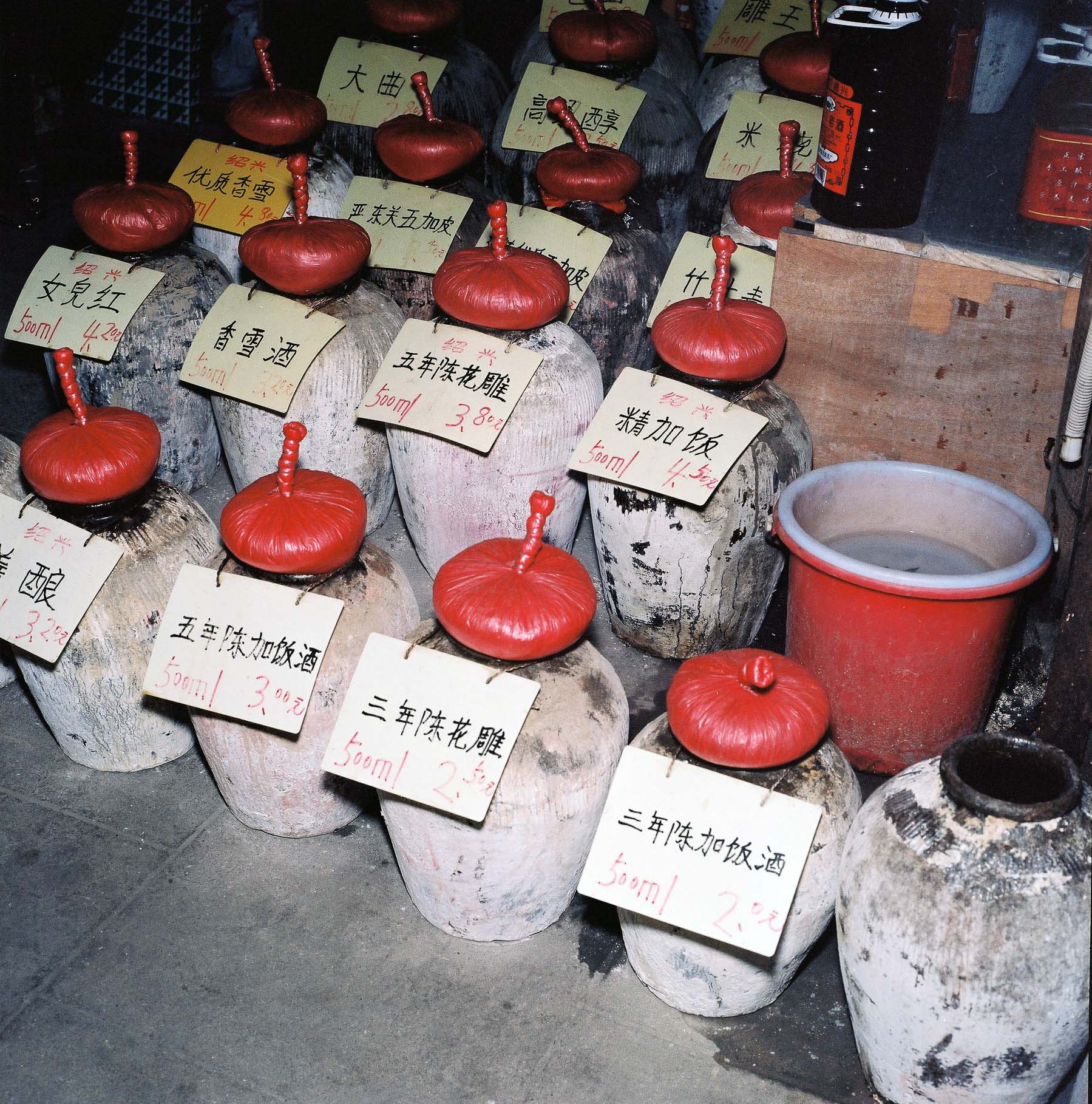 A collection of rice jars with red lids and chinese written labels. 