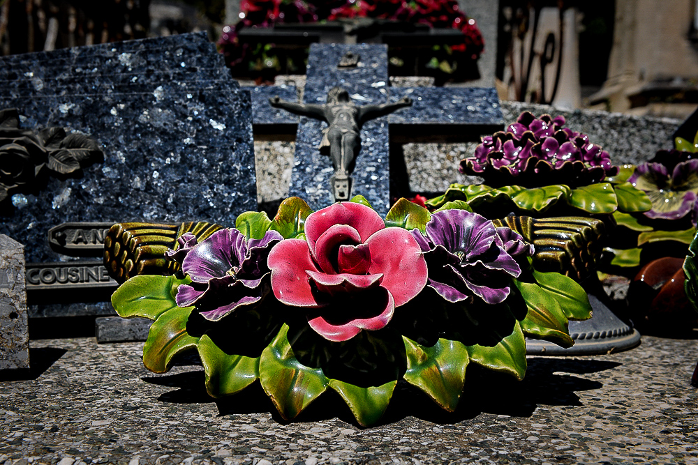 Well kept, brightly coloured majolica flower decorations in a French grave yard. 