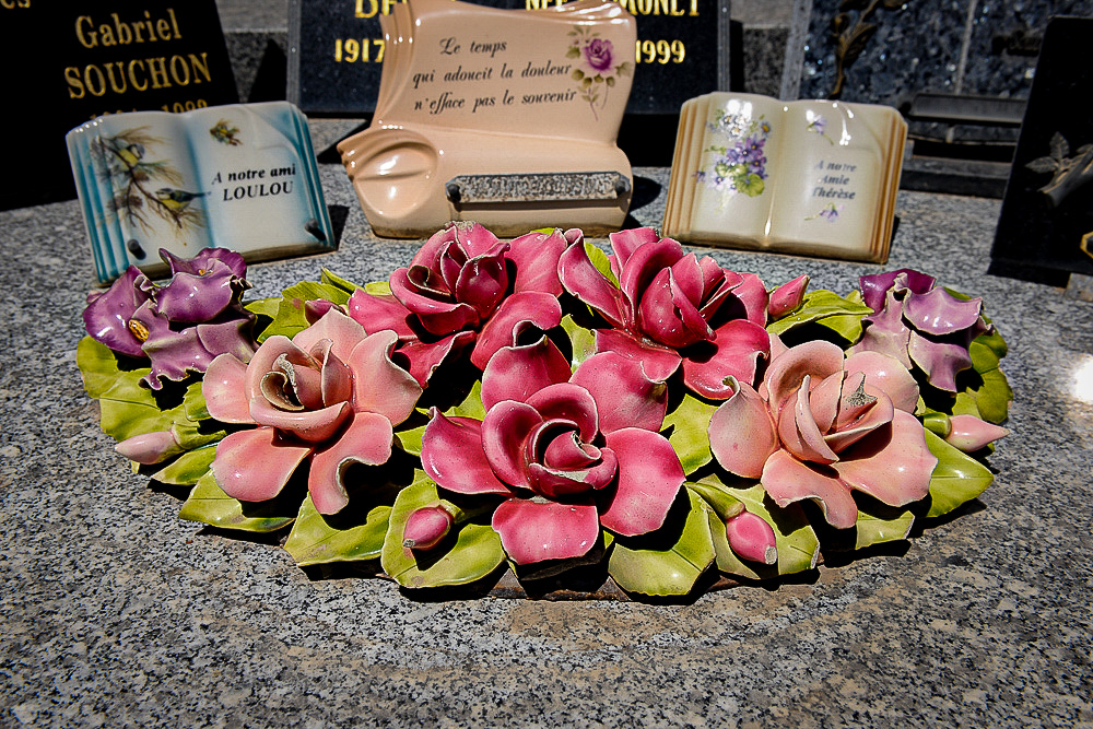 Horizontal ceramic pink flower arrangement displayed together with majolica books , the open pages decorated with scene from nature together with a verse. 