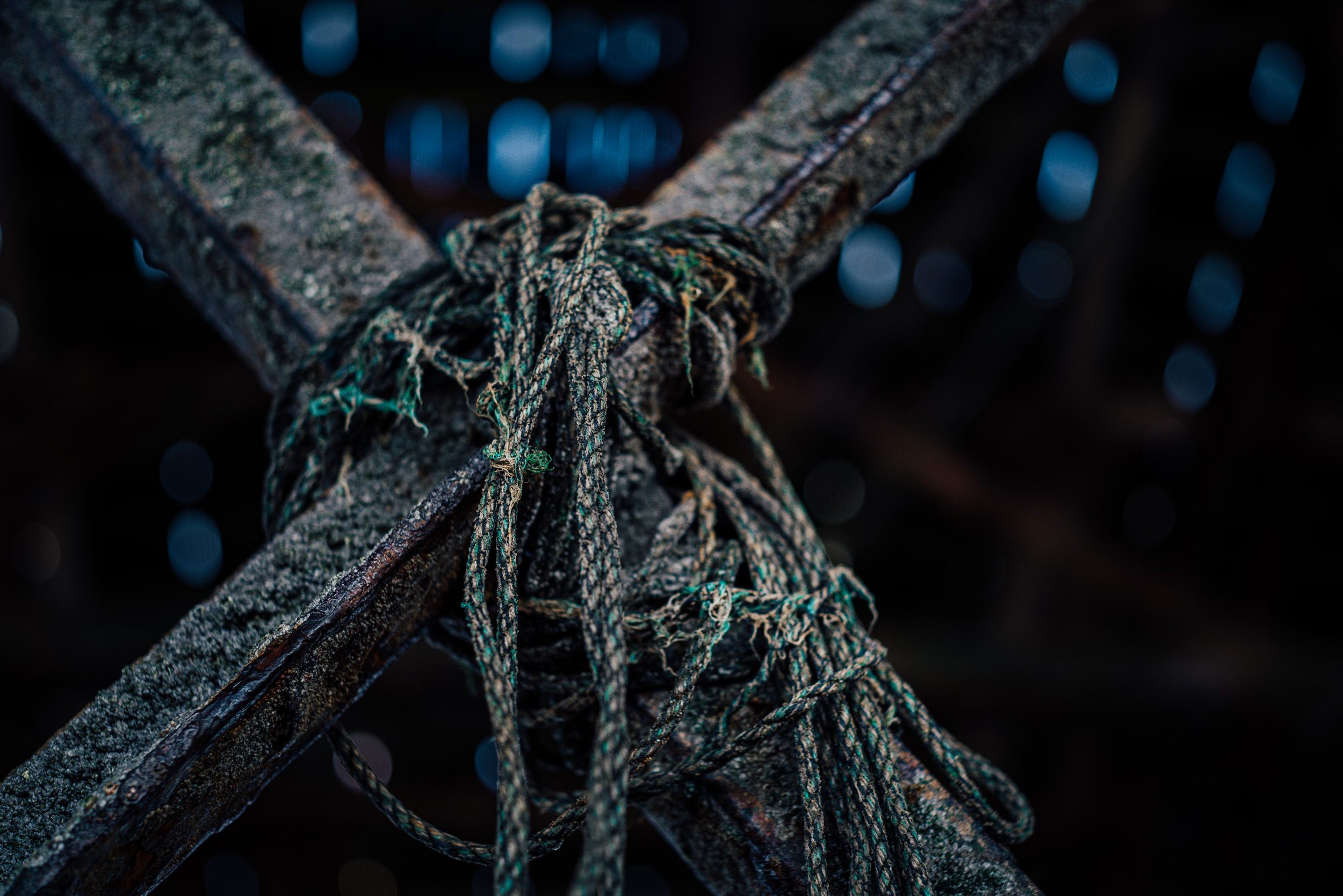 Rope entangled around the cross of a rusted steel structure. 