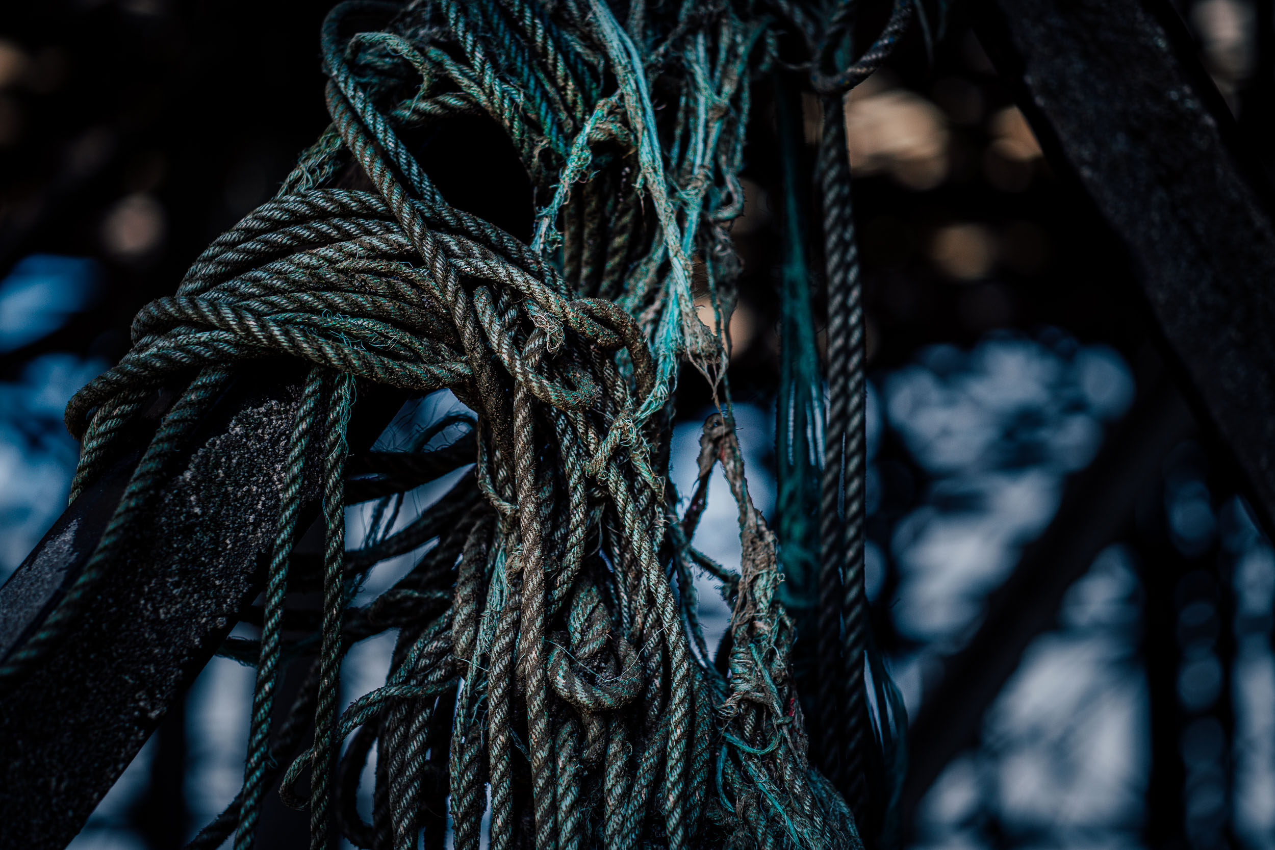 A tangled collection of blue green rope hanging off a rusted steel structure. 