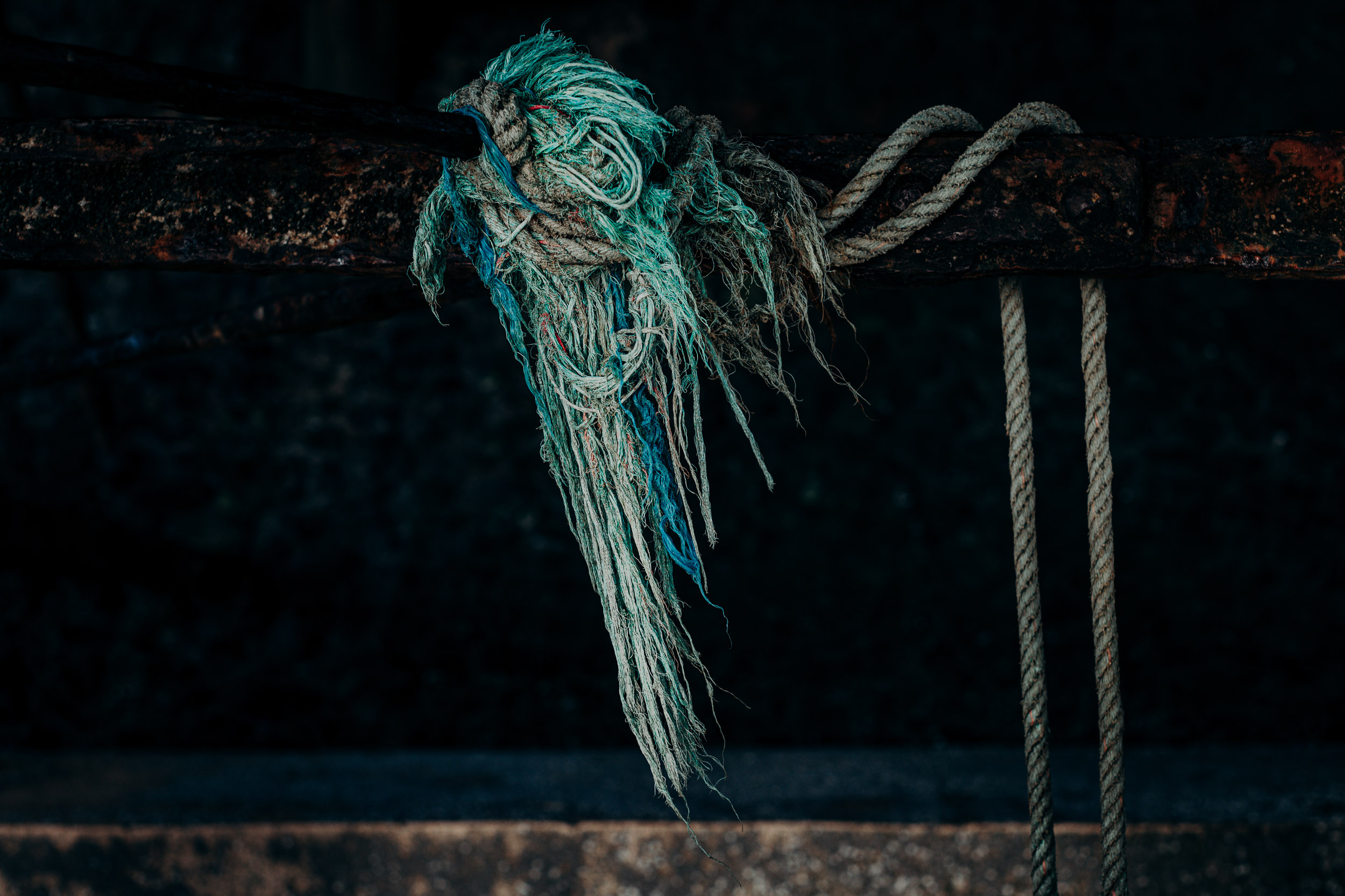 A cluster of discarded blue fishing nets, in the shape of a wing  washed up against railing underneath the Blackpool pier. 