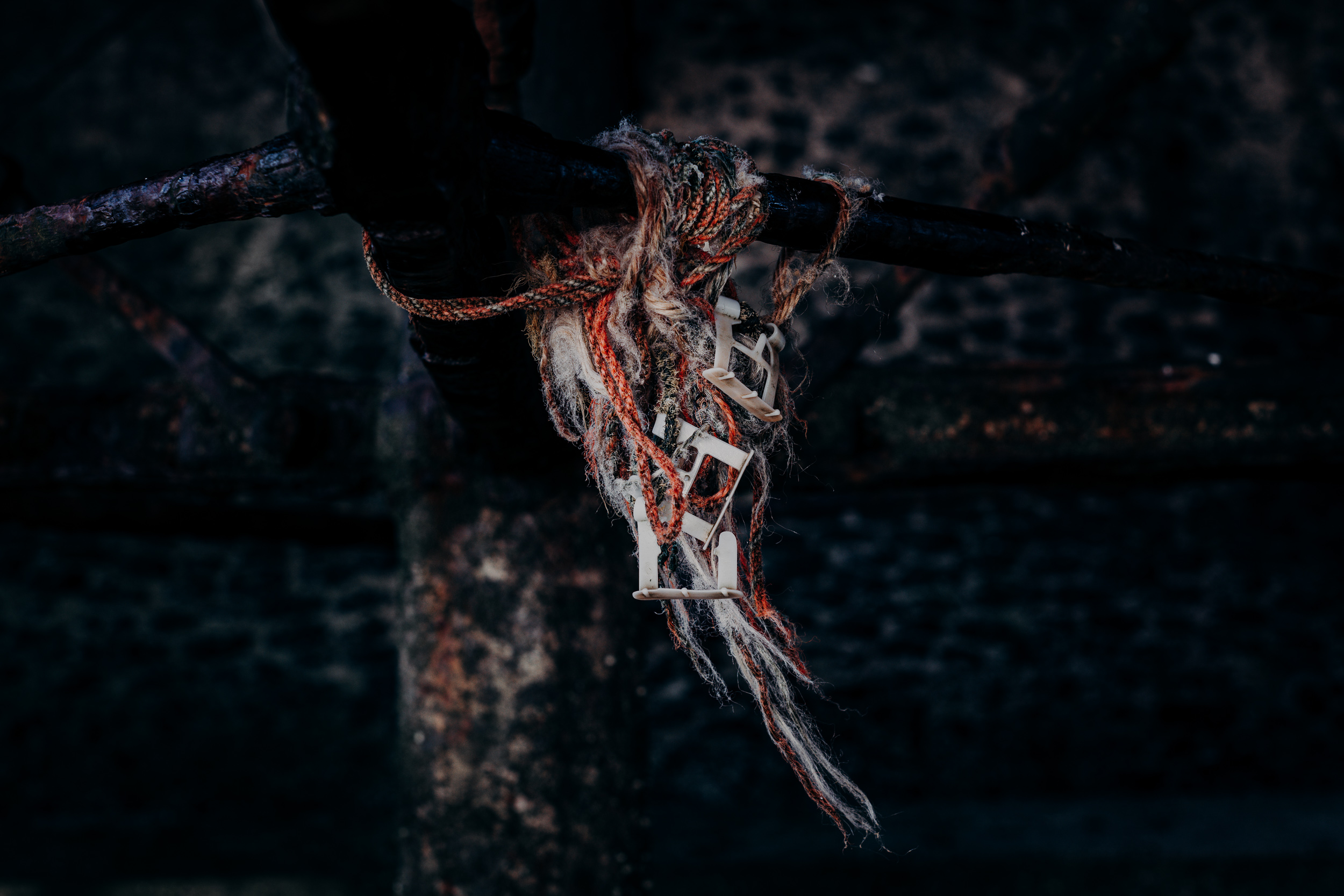 A cluster of orange rope, nets and plastic debris entangled around a rusted pole. 