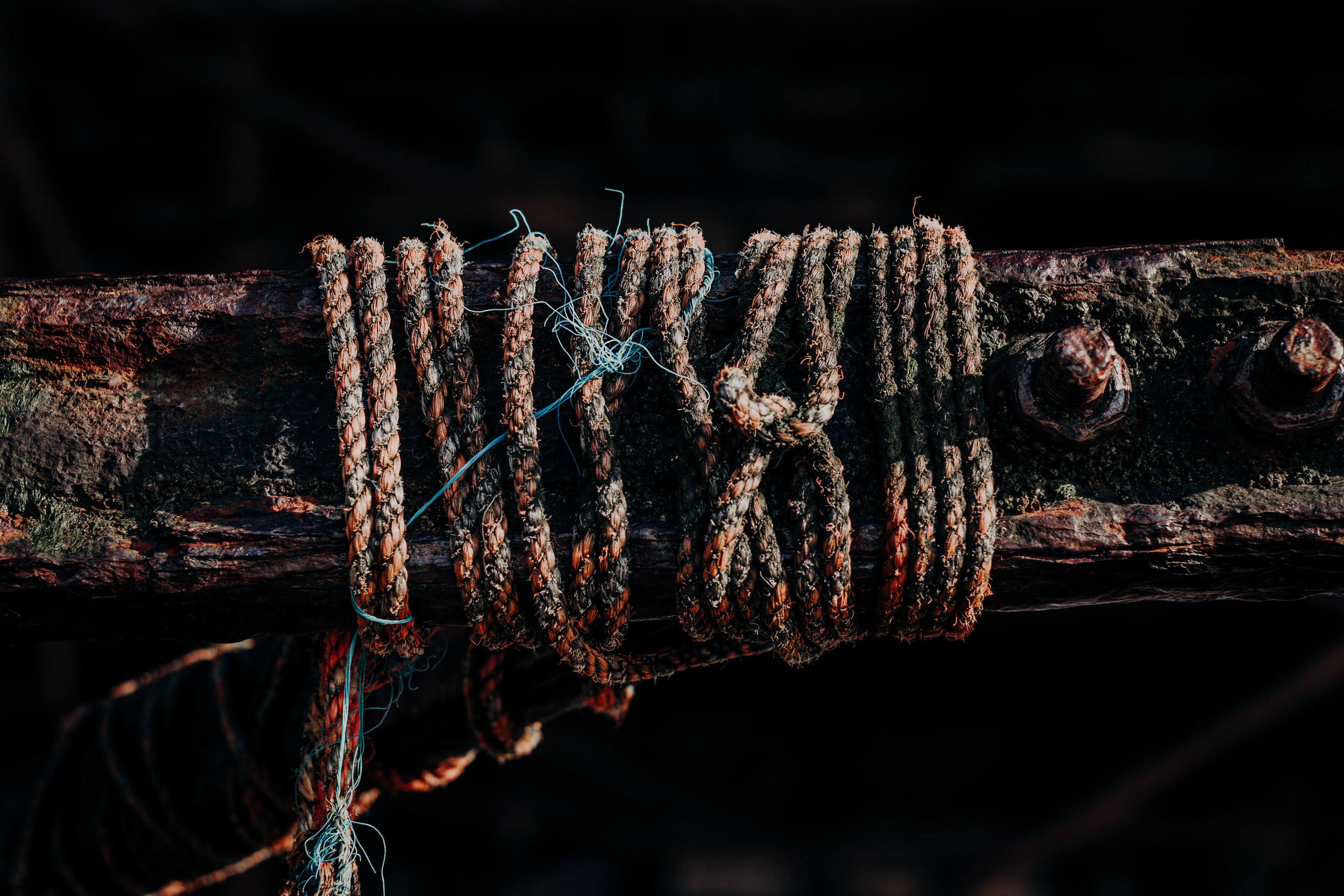 Two-tone rope and discarded fishing nylon lines knotted around a steel balustrade. 