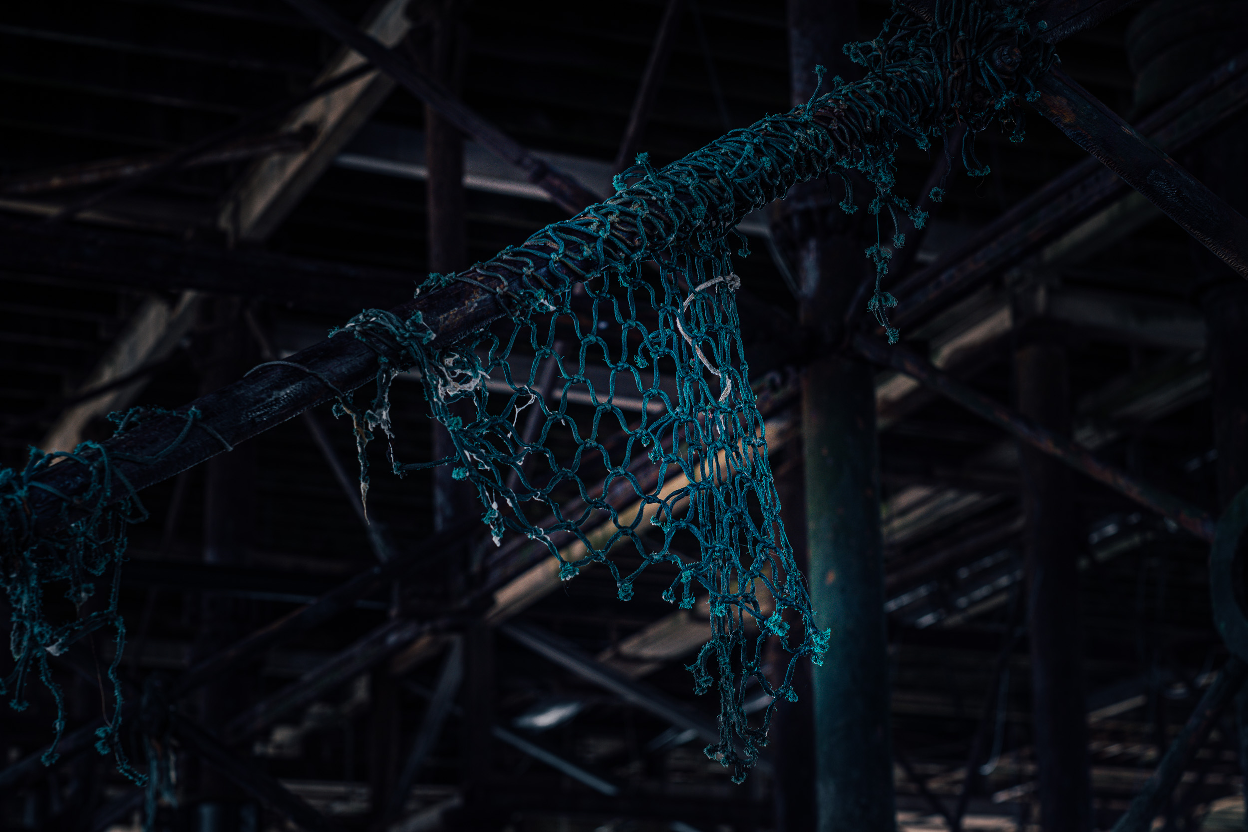 Washed-up, abandoned fishing net attached to a rusted wrought iron railing. 